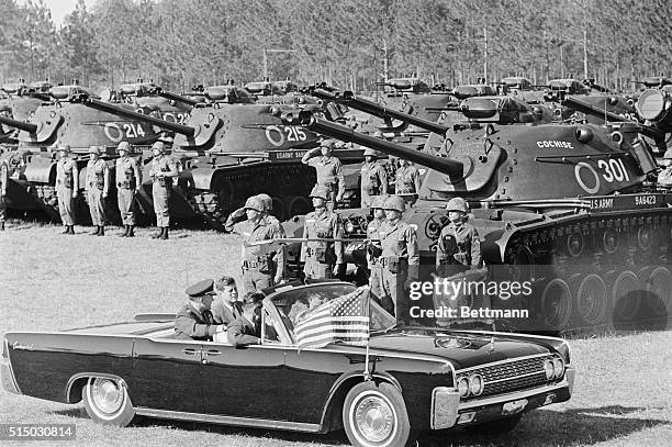 President John Kennedy rides in a cadillac convertable with Army Chief of Staff, Maxwell Taylor, as he inspects the troops and equipment at Fort...