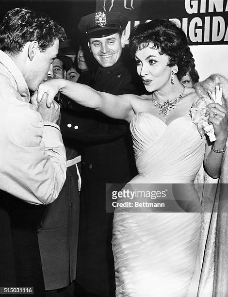 Italian actress Gina Lollobrigida extends her hand for a kiss by admirer Ed Herbich at the New York premiere of her latest film Beautiful But...