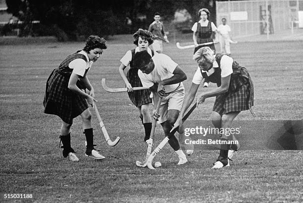 Puttaswami, graduate student from India, , runs into some brisk opposition from the distaff side in the weekly field hockey game between the men from...