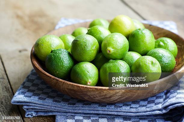 key limes, citrus aurantiifolia, in a wooden bowl - lime fotografías e imágenes de stock