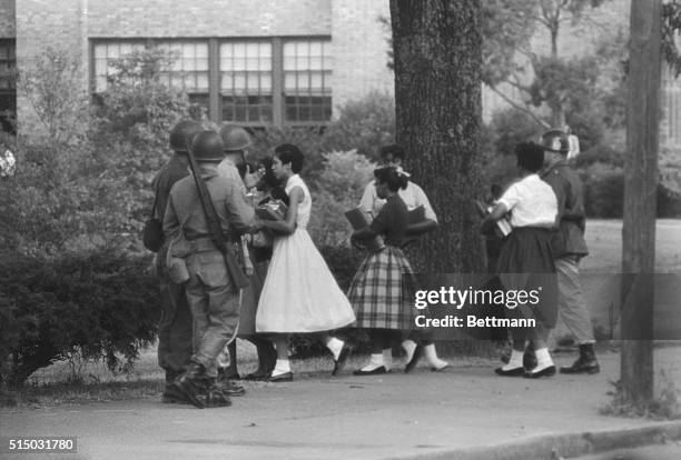 The group of nine African American students walk past members of the National Guard as they use a side door to enter Central High School in Little...