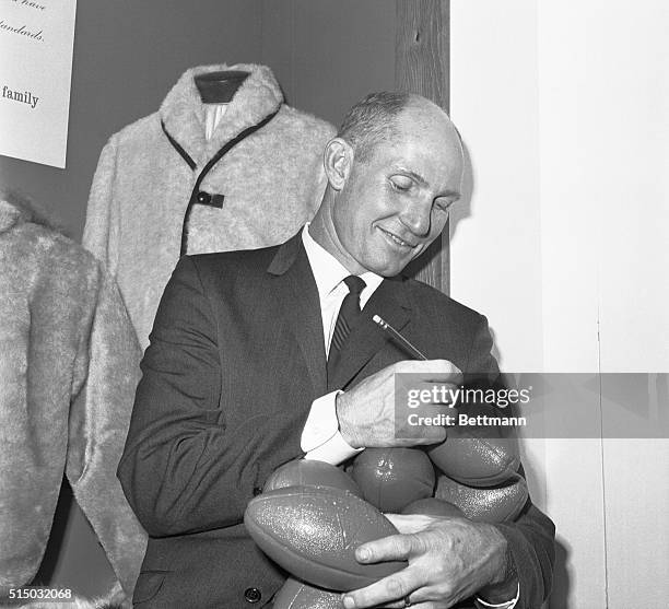 Giants' star Y.A. Tittle holds and autographs seven footballs October 29th at exhibit at the New York Trades show Building. The balding, 35 year old...