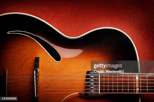 guitar leaning against red wall - guitar photos et images de collection