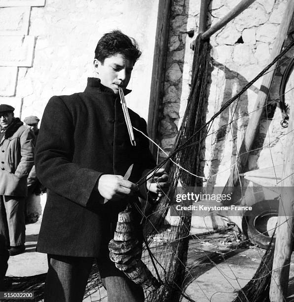 Fisherman repairing a fishing net in Marseille, France, in 1956.