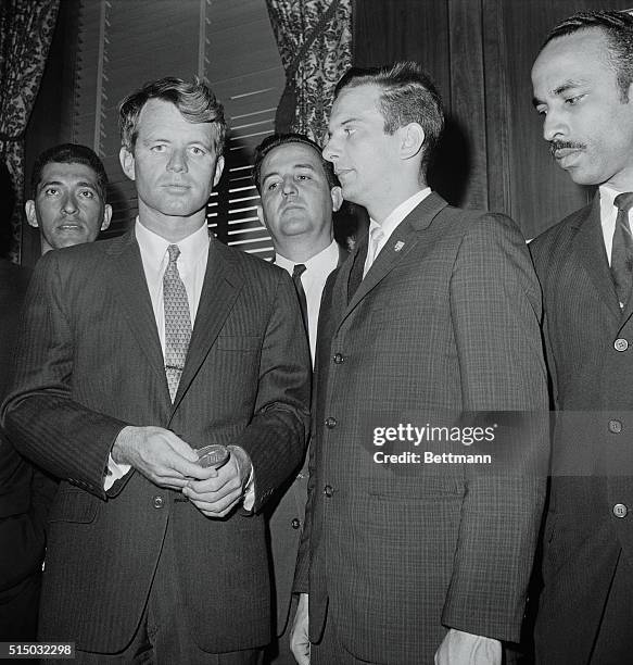 Attorney General Robert F. Kennedy holds medallion presented to him today by Jose A. Perez, commander of the 2506 Brigade from the Cuban Bay of Pigs...