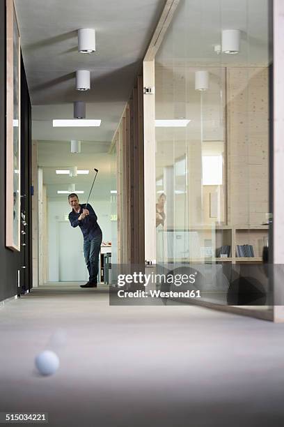 business man playing golf in corridor of modern office - escapismo foto e immagini stock