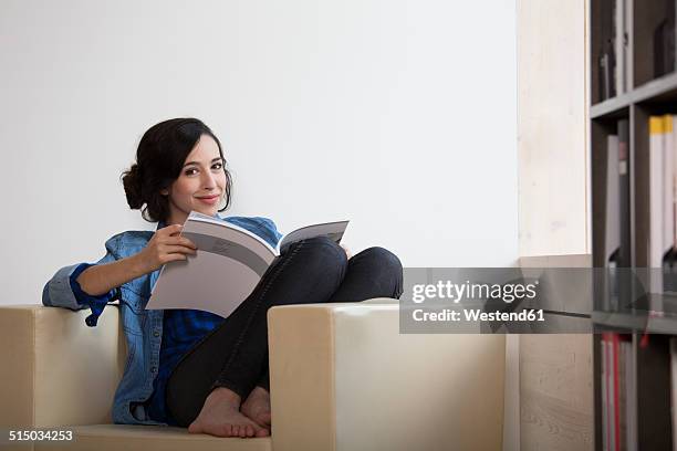 portrait of business woman sitting on armchair with magazine - frau zeitschrift liest stock-fotos und bilder