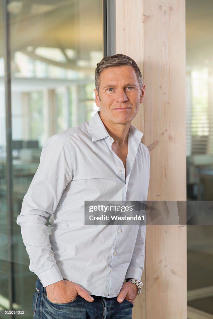 Portrait of smiling creative business man in front of glass pane