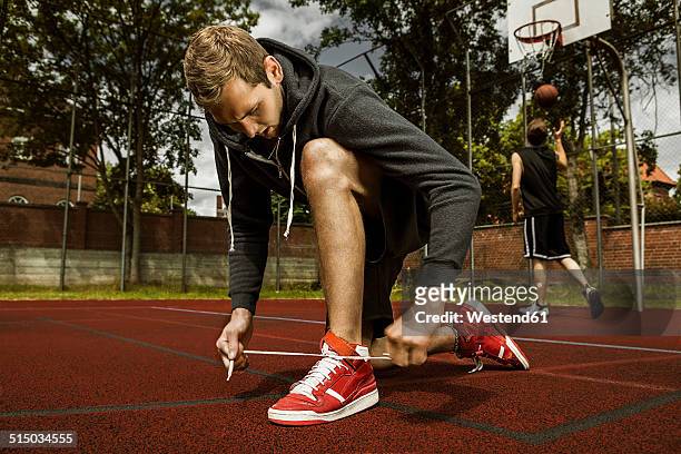 young basketball player doing up the shoelaces - amarrar o cadarço - fotografias e filmes do acervo