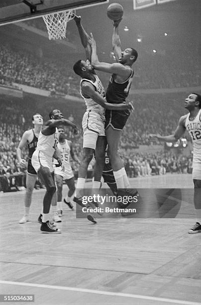 Boston: Bill Russell of the Celtics gets Warriors' Wilt Chamberlains' elbow in his mouth as he tries to block shot as they both leap. Action took...