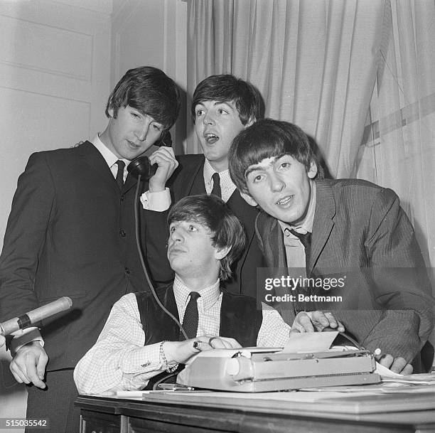 The Beatles, Great Britain's gyrating song sensation, gather around phone in their Hotel Plaza suite after arriving in New york Feb. 7. Airport...