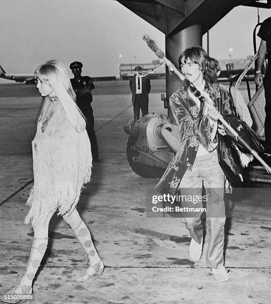 Beatle George Harrison and his wife make a colorful couple 8/9 as they arrive at John F. Kennedy Airport from San Francisco.