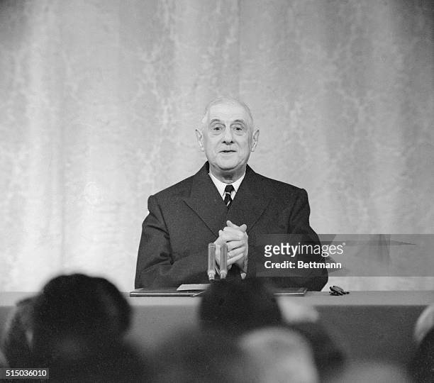 President Charles De Gaulle, with a sheepish grin on his face, clasps his hands during his press conference at Elysee Palace here. De Gaulle in...