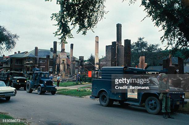 Soldiers patrol along row of fire-gutted homes following the riot.