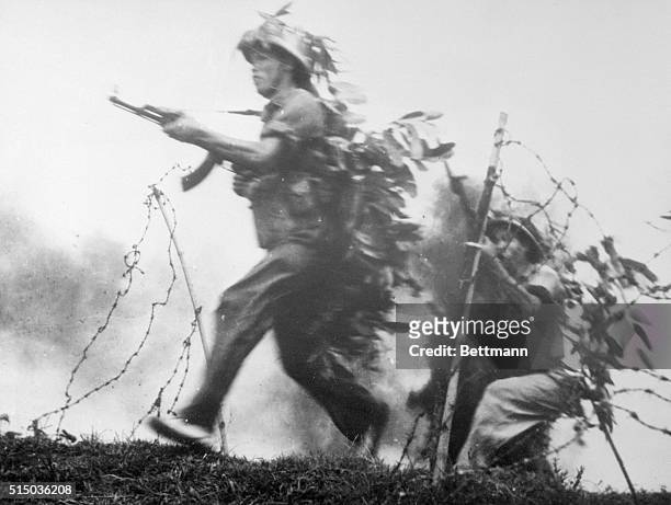 Members of the No. 3 Company of the North Vietnamese Army run along barbed wire during a training exercise. The company has been awarded two exploit...
