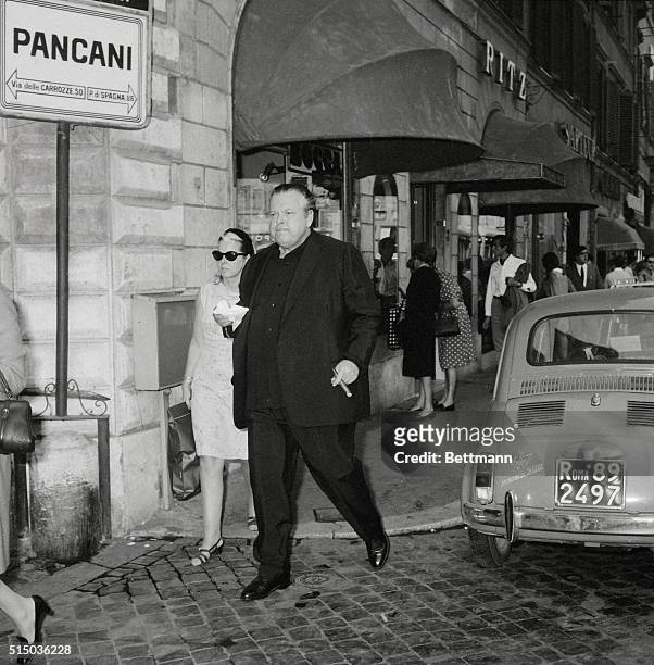Actor-director Orson Welles and his secretary Miss M. Coppiello go for a stroll on Rome's fashionable Via Condotti. He is appearing in House of Cards...