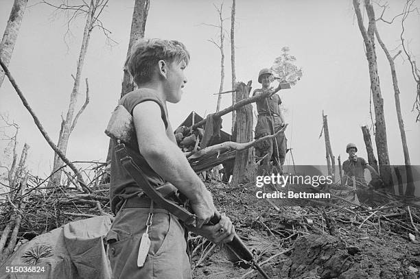 Member of the 4th Infantry Division looks up at another soldier who is holding a flower bouquet atop Hill 875 near Dak To, South Vietnam. The bouquet...