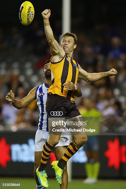 Sam Mitchell of the Hawks punches the ball away from Lindsay Thomas of the Kangaroos during the NAB CHallenge AFL match between the Hawthorn Hawks...