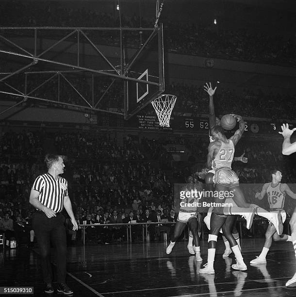Joe Caldwell , of the St. Louis Hawks, has his shot blocked by Knicks' Walt Bellamy as he rides in on the back of New York's Willis Reed during their...