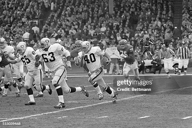 Pete Banaszak with running interference from teammates Gene Upshaw and Wayne Hawkins of the Oakland Raiders, rambles around end in the game against...