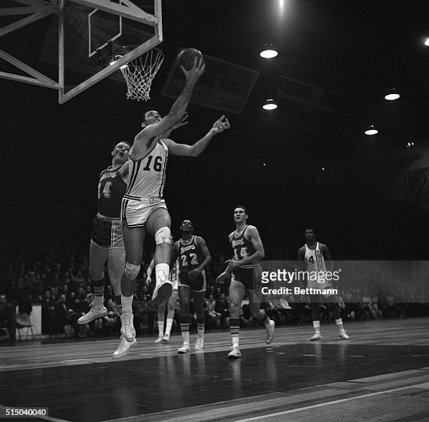 Jerry Lucas , Cincinnati Royals, drives under the basket and scores as Darrell Imhoff of the Los Angeles Lakers, tries to stop the play.