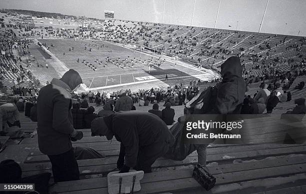 Bundled fans brush snow off seats at Lambeau Field here 12/31 as the Packers warm up for their NFL championship game with the Dallas Cowboys. The...