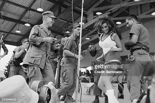 Raquel Welch dances on stage with a group of soldiers during a Bob Hope USO show at Da Nang, Vietnam.