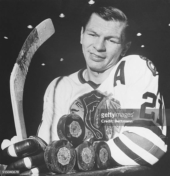 Black Hawks Stan Mikita can't help boosting his sights at this stack of hockey pucks that represents the hat trick, plus one that he scored during an...