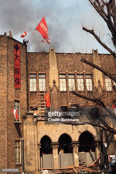 Radical student waves a flag from a tower of a building at Tokyo University, January 18, as police continue an 11-hour battle to regain the campus...