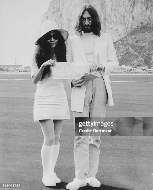 Beatle John Lennon and his bride, Japanese-born Yoko Ono, hold the marriage certificate following their registry office wedding here on March 21st....