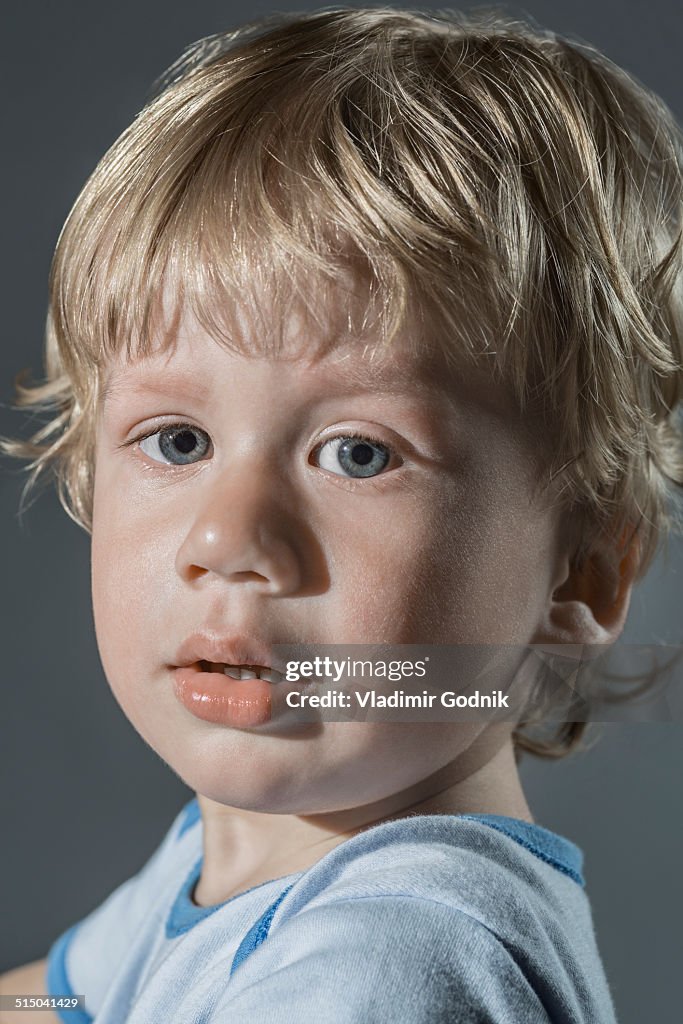 Portrait of cute boy over gray background