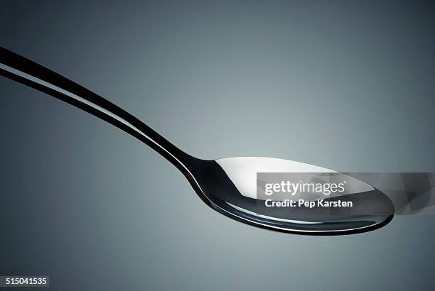 close-up of a spoon in mid-air - cucchiaio foto e immagini stock