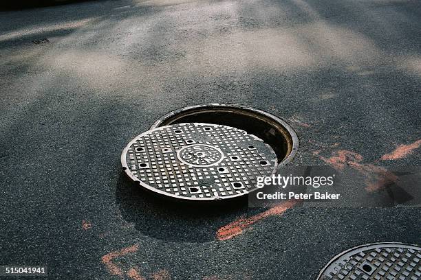 a manhole cover partially removed, close-up - égout photos et images de collection