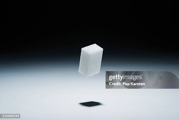 a cube of sugar in mid-air - lebensmittel rechteck stock-fotos und bilder