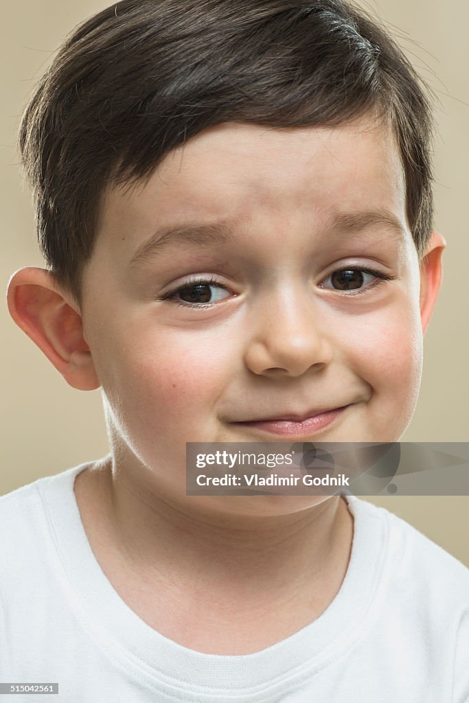 Portrait of boy smiling against beige background