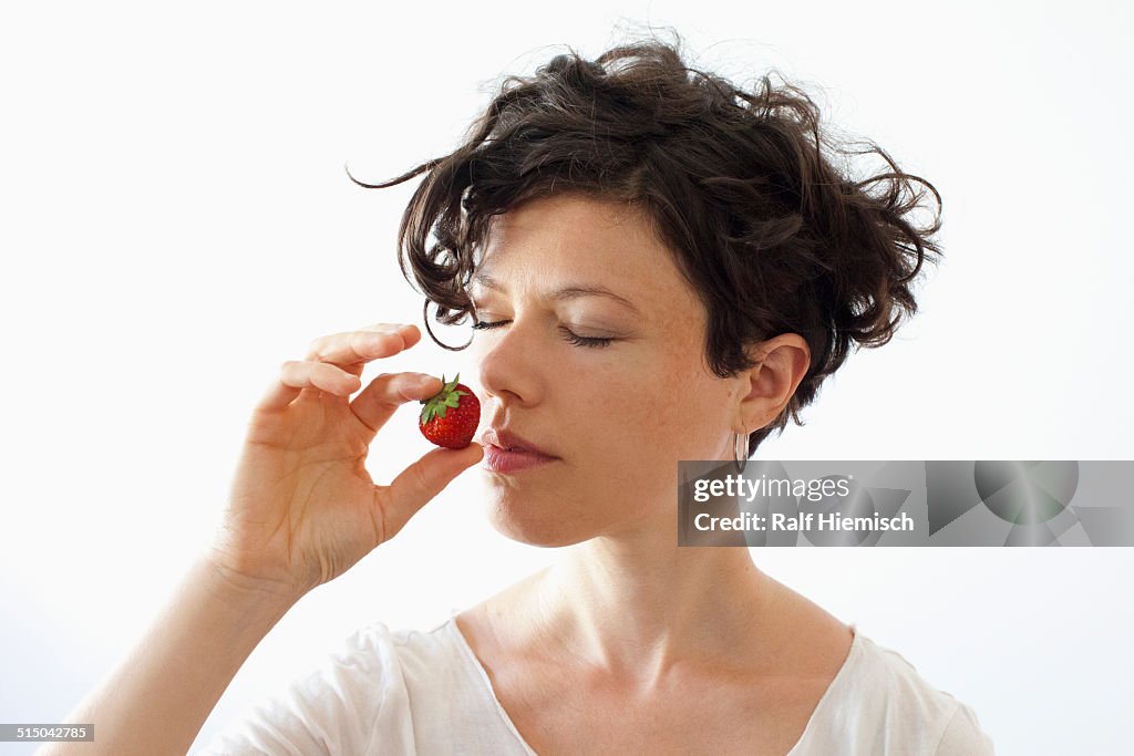 A woman smelling strawberry over white background