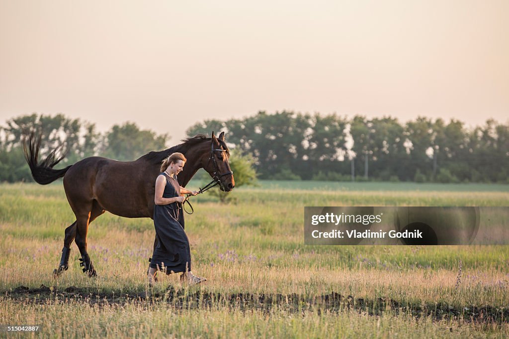 Mid adult woman with horse walking on field