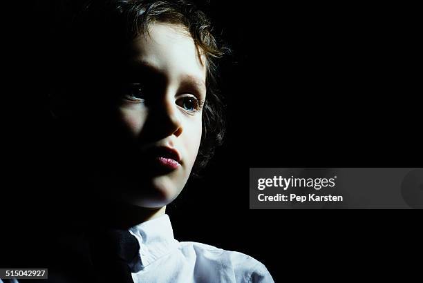 a young boy looking away in contemplation - clair obscur stockfoto's en -beelden