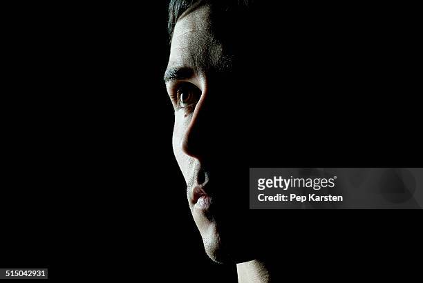 a man looking away contemplatively - people on black background stock-fotos und bilder
