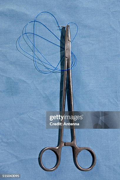 a pair of surgical scissors holding a suture needle and thread, directly above - surgical needle ストックフォトと画像