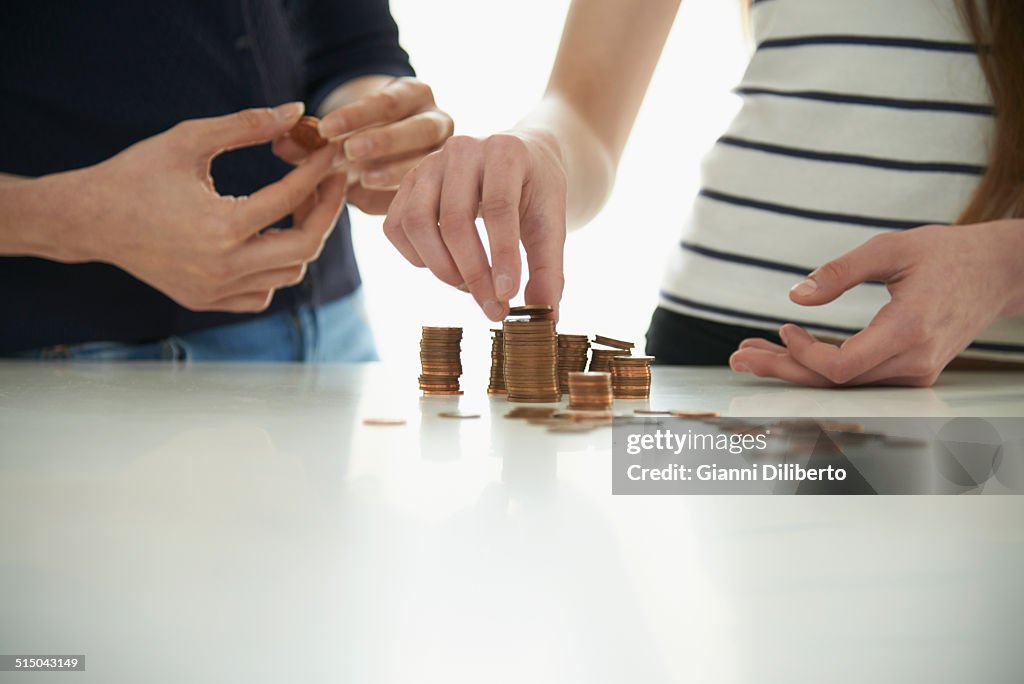 Midsection of mother and daughter stacking coins at table