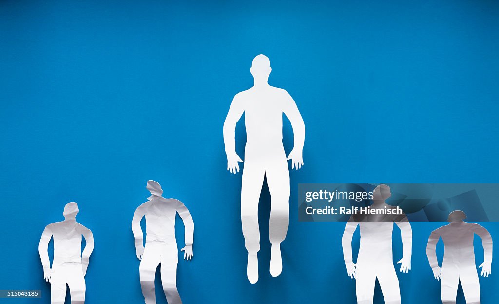 Paper businessman flying while colleagues standing down representing leadership over blue background