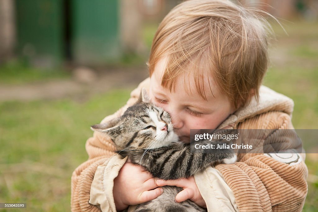 Baby girl holding cat and kissing