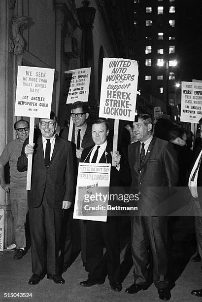 United Auto Workers Union President Walter Reuther leads a parade of striking Los Angeles Herald Examiner workers around the fenced and barricaded...
