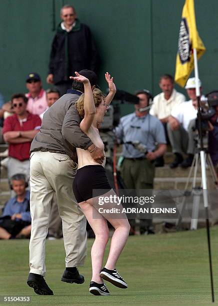 Streaker is taken into custody on the 18th green after she made her dash shortly after Tiger Woods of the US completed his second round on the Old...