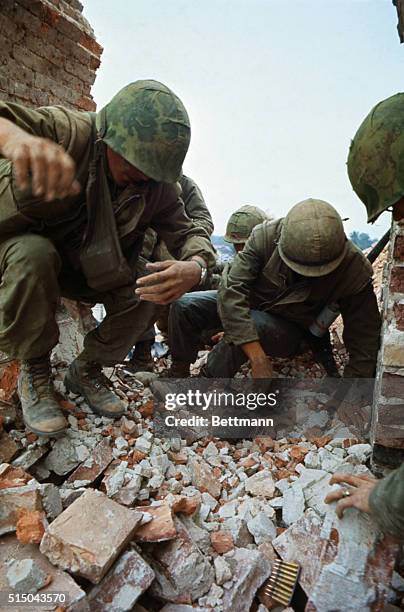 U.S. Marines dig with their hands through brick rubble burying PFC ...