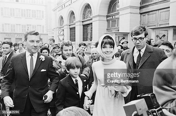 Helped by Swiss policemen, actress Audrey Hepburn and her husband, Italian psychiatrist Dr. Andrea Dotti, make their way through a crowd of newsmen...