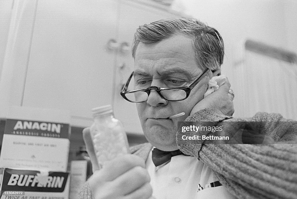 Man Holding Pills While Taking His Temperature