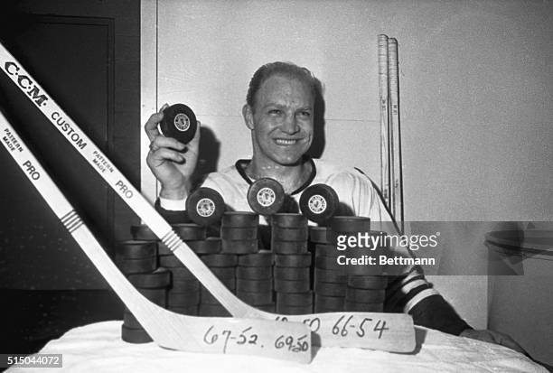 Chicago Black Hawks scoring ace Bobby Hull holds up what he hopes is a record breaker as he poses behind a small mountain of pucks prior to a workout...