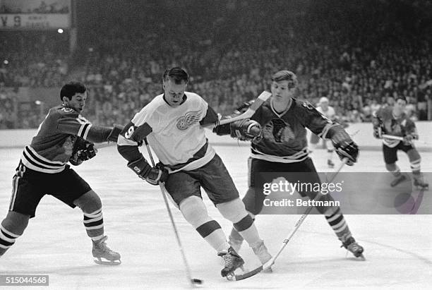 Detroit's right wing Gordie Howe (90 can't be corralled by Black Hawks defense men Chico Maki and Keith Magnuson in first Stanley Cup game 4/8. The...